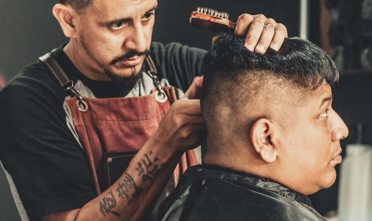 Un barbero latino cortando el cabello a un cliente