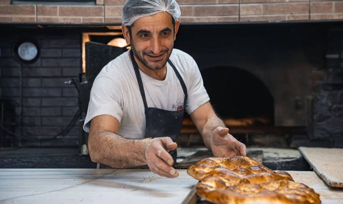 Un panadero presentando su pan frente al horno de leña